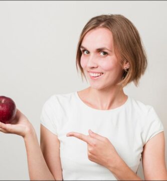 Imagen de una mujer sosteniendo una manzana que es una fruta beneficiosa para el colesterol bueno