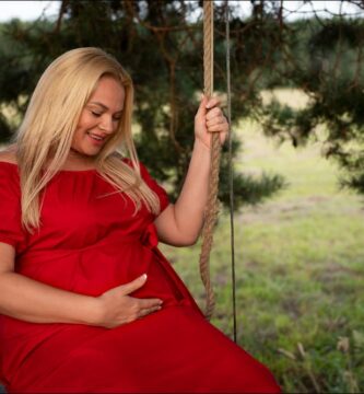 Foto de mujer rubia con vestido rojo embarazada