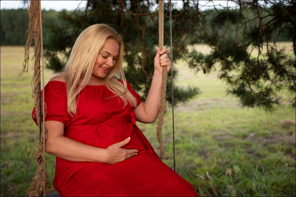 Foto de mujer rubia con vestido rojo embarazada