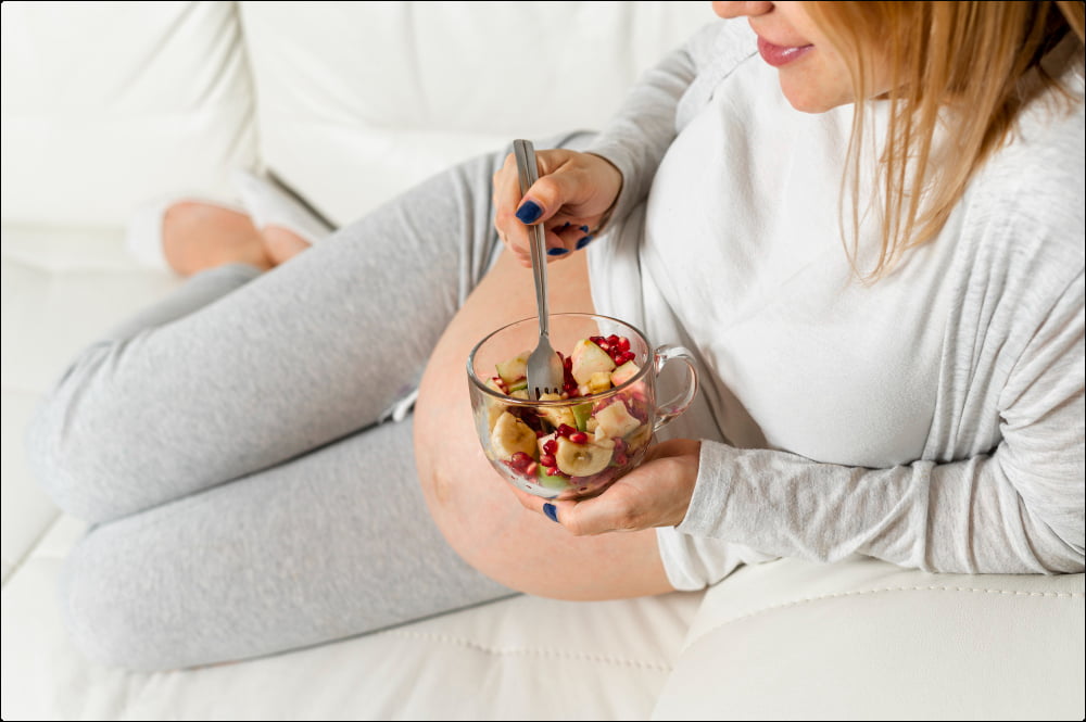 foto de una mujer embarazada con un de frutas que representa la importancia de la alimentación en la fertilidad