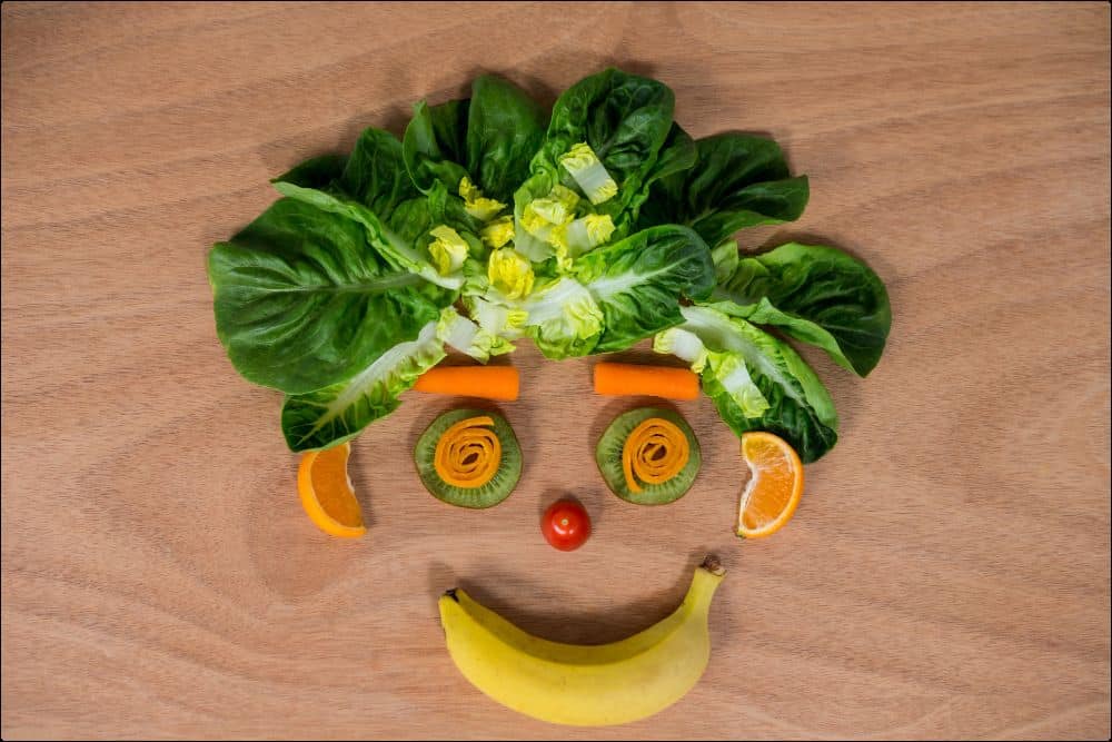 cara hecha con frutas y verduras que representan a los alimentos que calman el sistema nervioso
