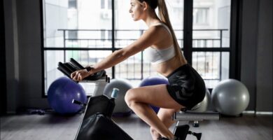 Toma lateral de una mujer que está entrenando con una bici estática en su casa