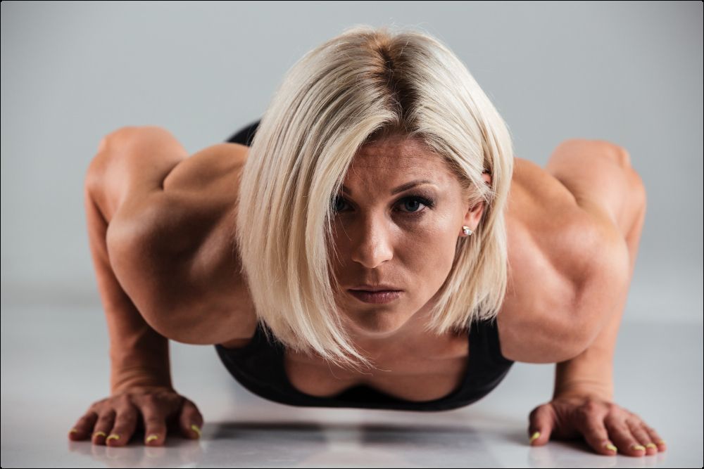 imagen de una mujer con definición una definición muscular óptima haciendo flexiones en el suelo