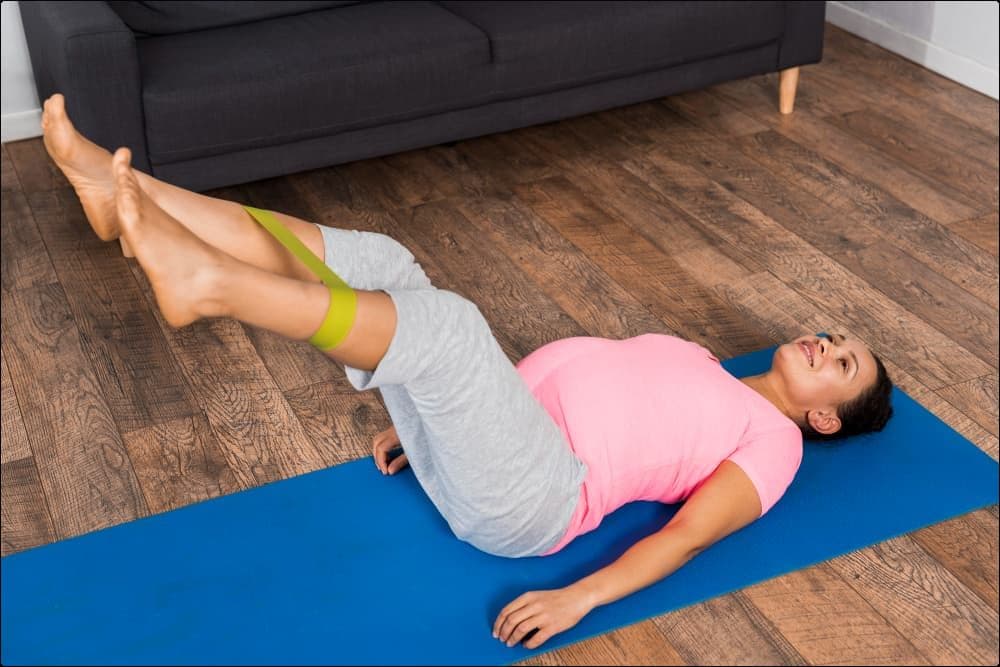 mujer realizando sobre una esterilla azul ejercicios para mejorar la circulación de las piernas con varices