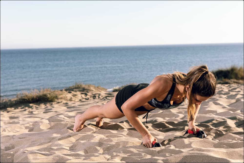 imagen de una mujer que está haciendo un entrenamiento en la arena de la playa