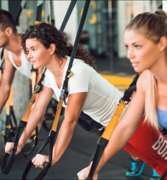 Imagen de dos mujeres y un hombre realizando ejercicios de entrenamiento funcional en el gimnasio.