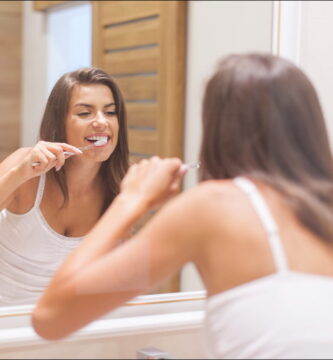 foto de mujer practicando una buena higiene bocal cepillándose mirándose al espejo