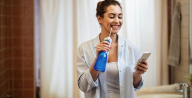foto de mujer usando un irrigador bucal mientras mira su teléfono