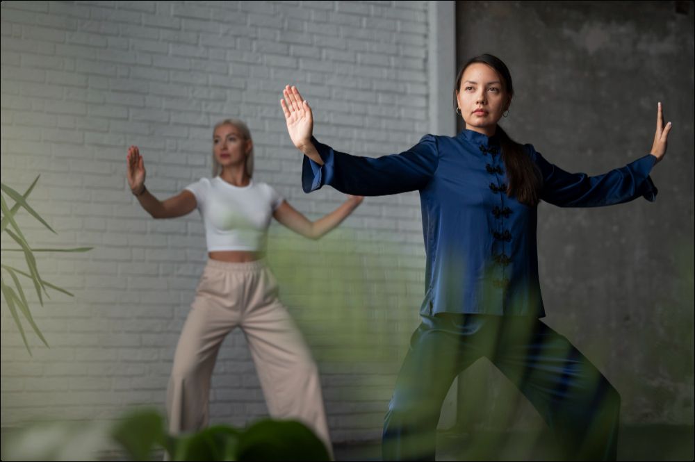 imagen de dos mujeres practicando taichi, una con el traje tradicional y la otra con ropa deportiva.