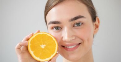 imagen de una mujer con una naranja uno de los alimentos con mayor proporción de vitamina c, algo que es bueno para la piel
